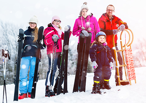 A family posing outside with their winter sports gear.