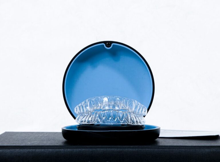 A clear plastic retainer sitting in a blue retainer case.
