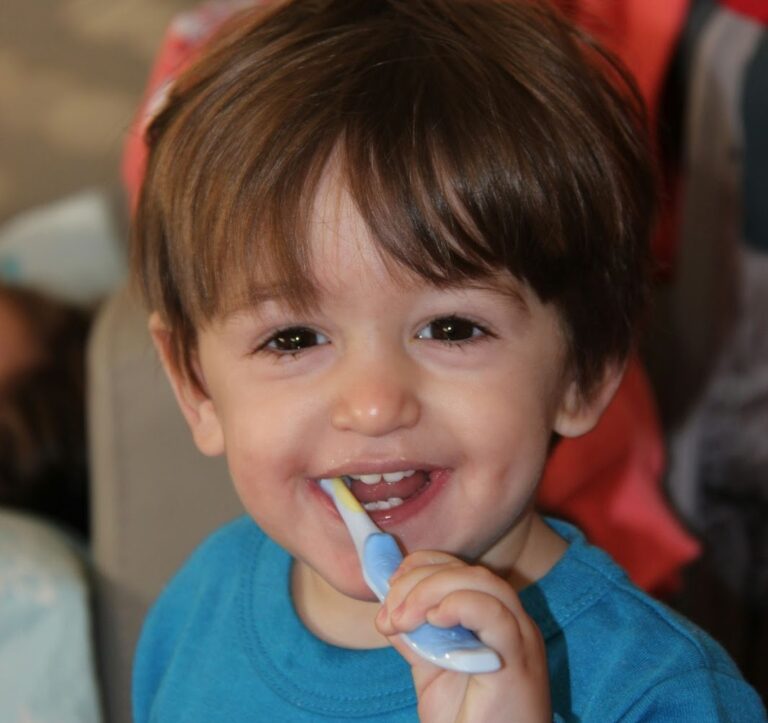 Little boy in blue shirt, brushing his teeth.
