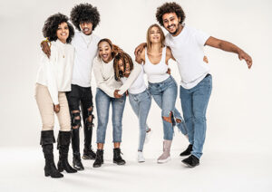 A family dressed in white shirts and blue jeans, standing in front of a white background.