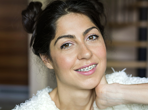 Smiling woman with dark hair in two buns and braces, looking at the camera.