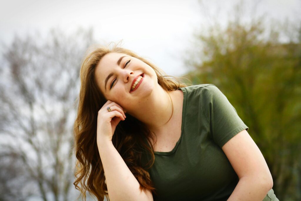 A woman in a green shirt leaning to her right and smiling.