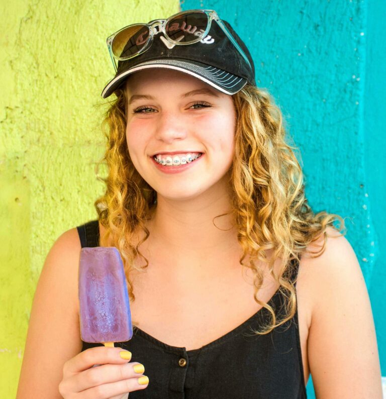 Happy girl with braces and a popsicle in hand.