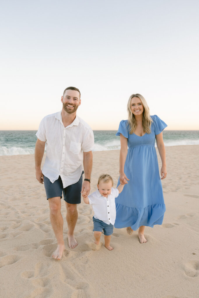 Dr. Blake Bean walking on the beach with his wife and young son, all smiling and holding hands