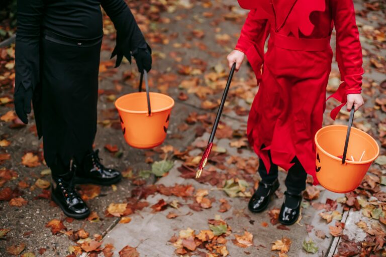 Kids dressed in costumes holding bright orange pumpkin buckets for candy, reminding families to plan ahead for safe trick-or-treating with braces.