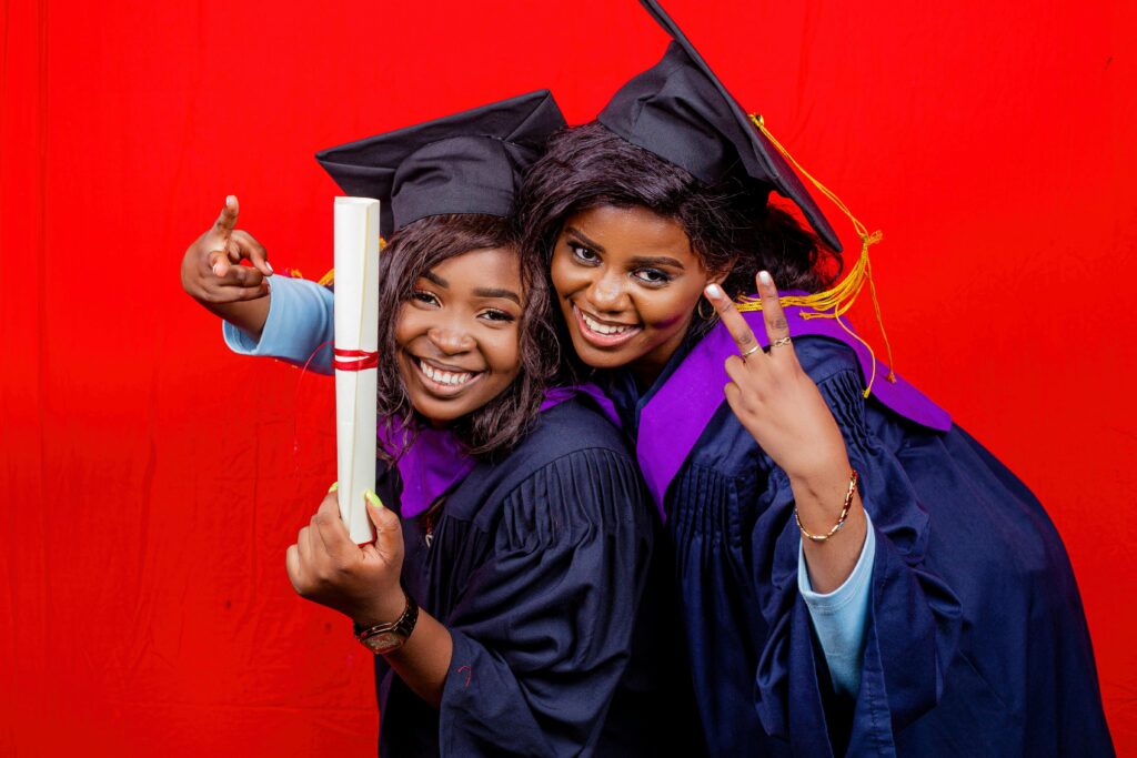 Two girls wearing graduation gowns and straight teeth.