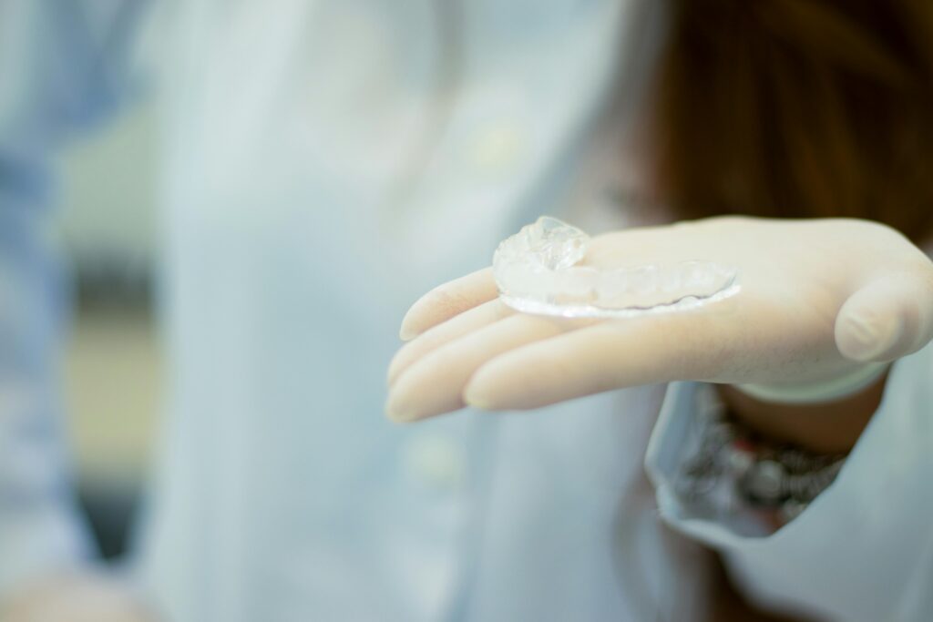 Clear braces on orthodontist's hand.