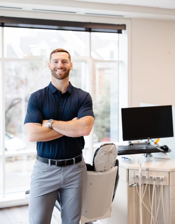 Orthodontist Dr. Blake Bean standing in front of a dental chair and dental equipment.